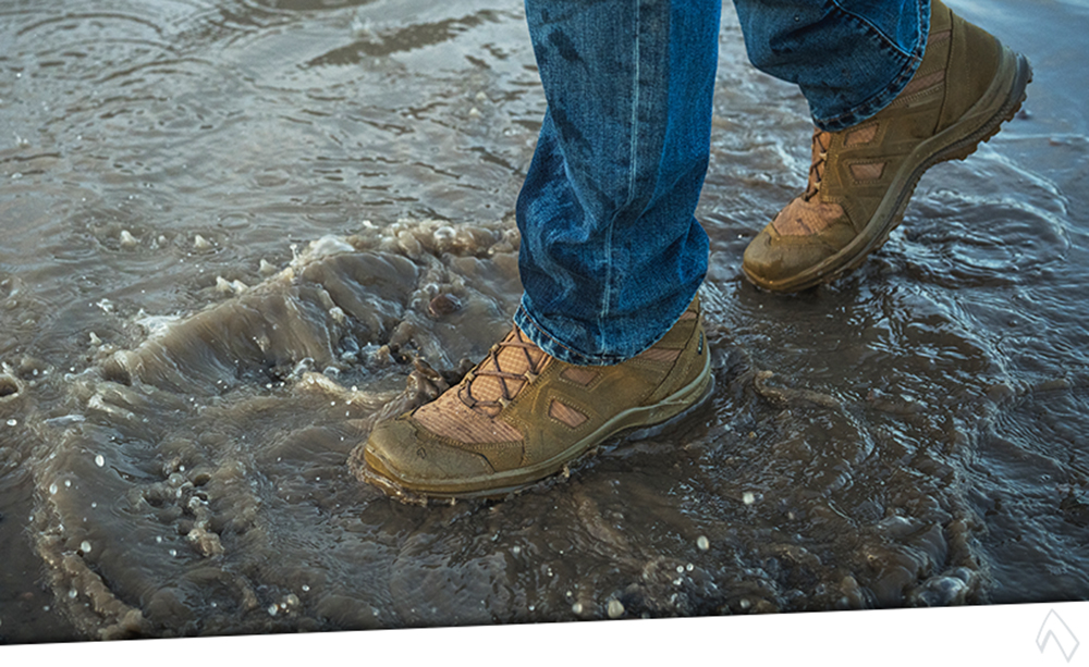 A person walking through water wearing HAIX footwear, showcasing durability and comfort in wet conditions.